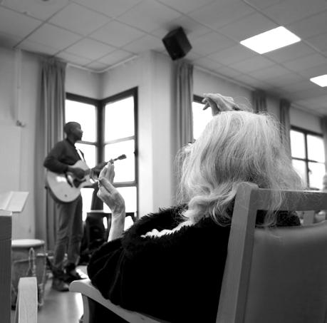Jean-Marc joue de la guitare devant une résidente à l’Hôtel-Dieu de Rennes, en noir et blanc.