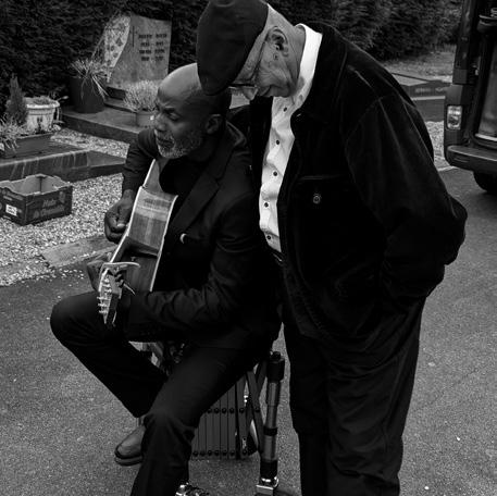 Jean-Marc à la guitare auprès d’un proche au cimetière de Rennes, en noir et blanc.